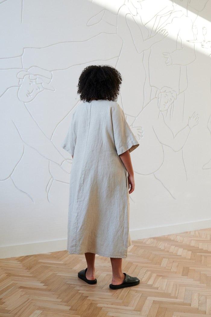 Back of a model in an A-line long linen dress wide sleeves