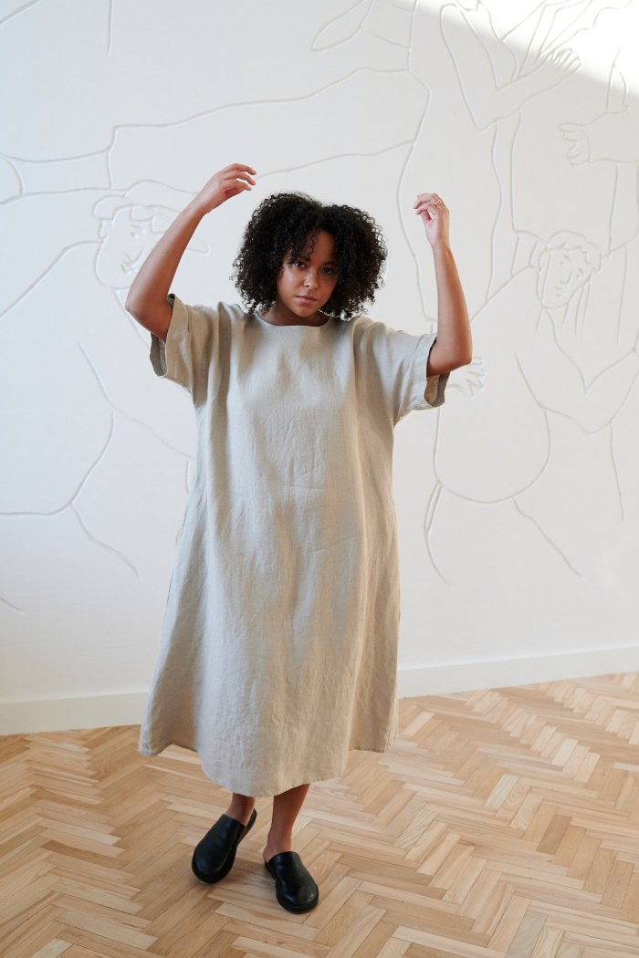 Model in an oversized long dress with dropped shoulders and wide sleeves