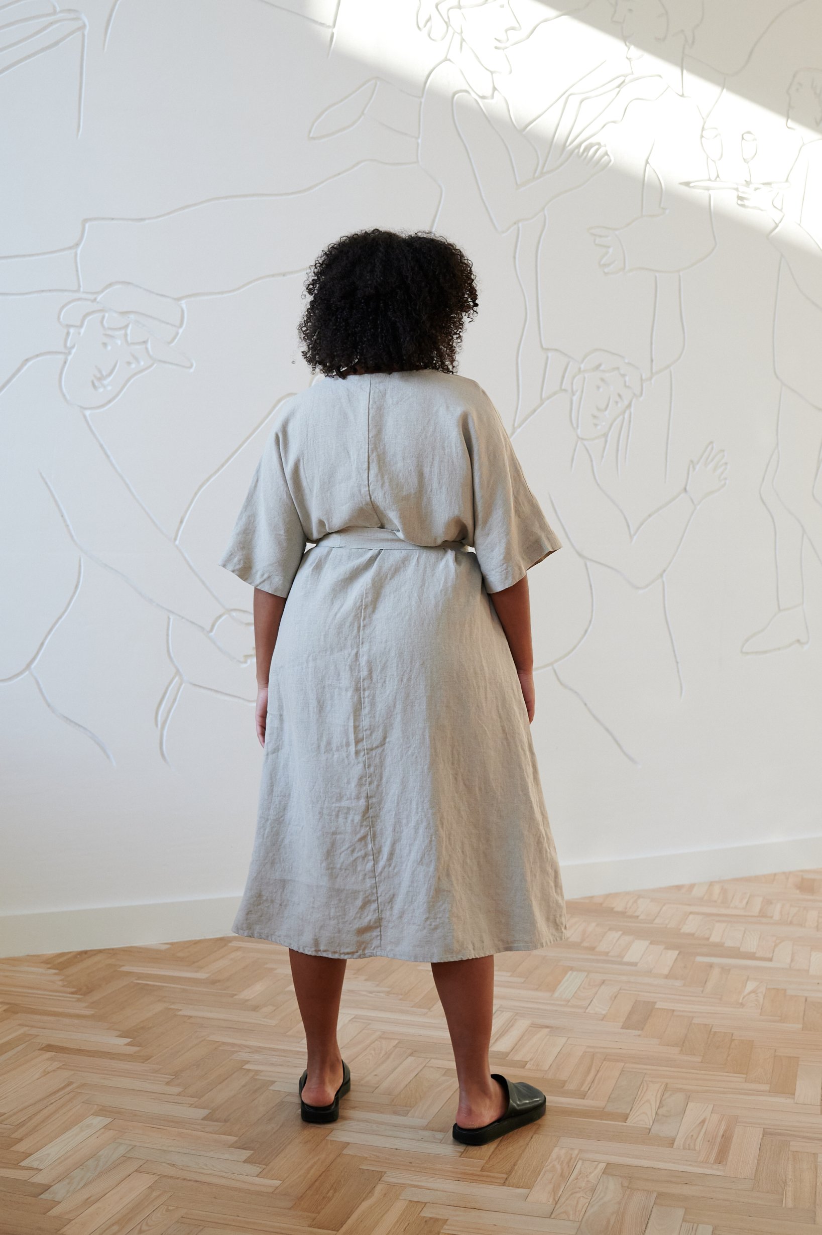 Back of a loose-fitting linen dress tied with a belt
