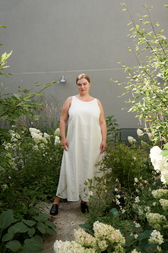 A curvy model wearing a milky white long linen dress with a higher round neckline