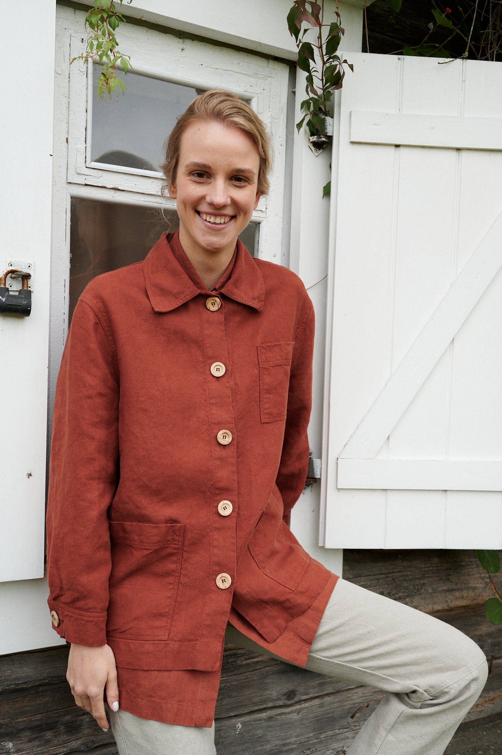 Front of a heavy linen utility jacket in terracotta with three pockets and wooden buttons