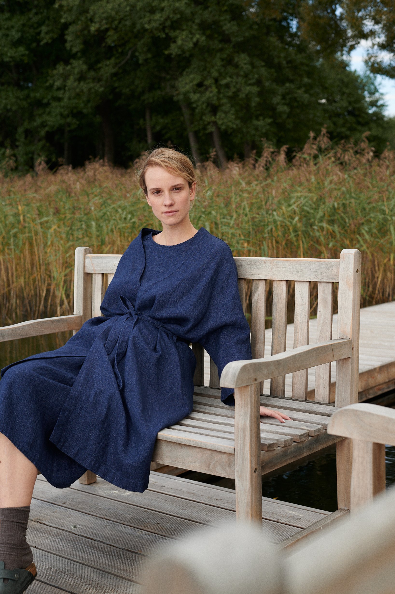 Woman in a navy blue linen wool blend jacket sitting on a bench