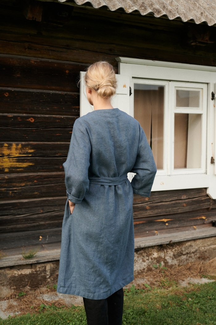 Back of a model wearing a blue linen wool blend jacket with a belt