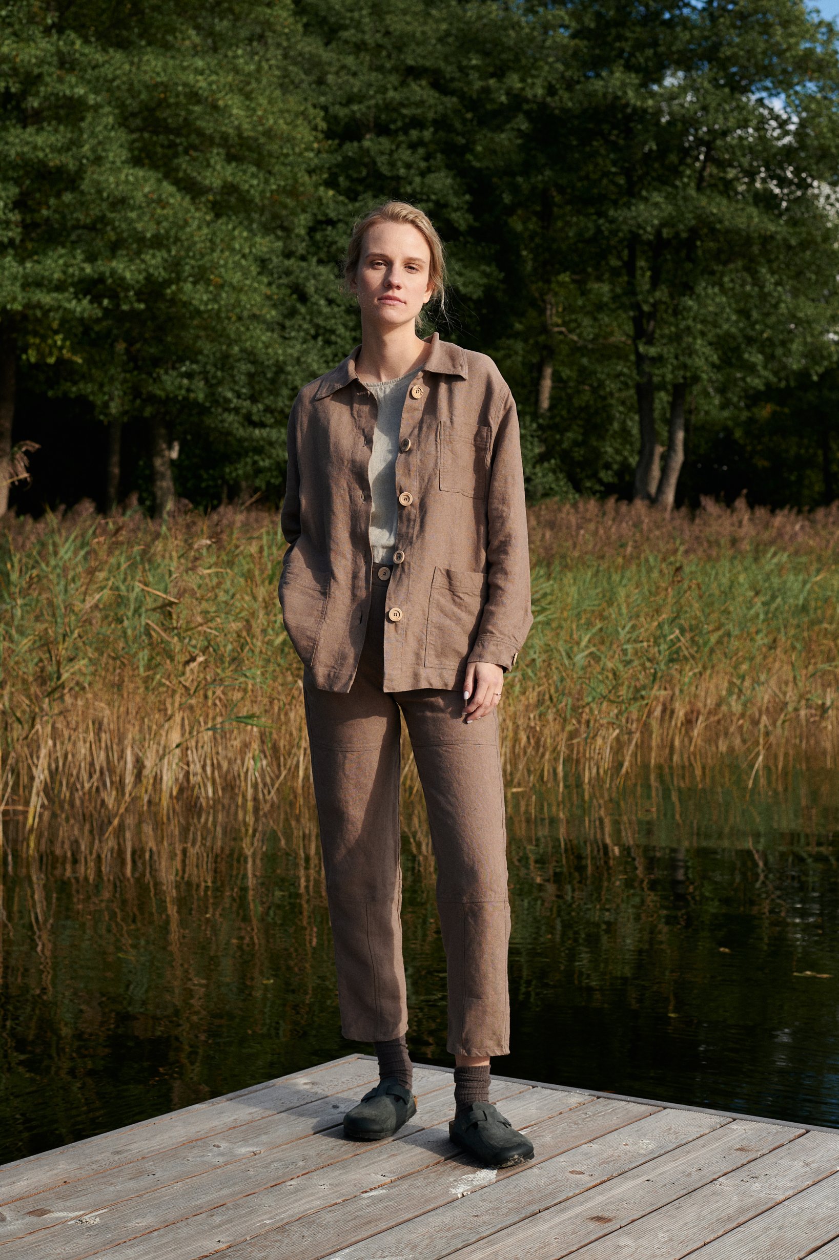 Model wearing an unbuttoned brown linen utility jacket and pants outfit
