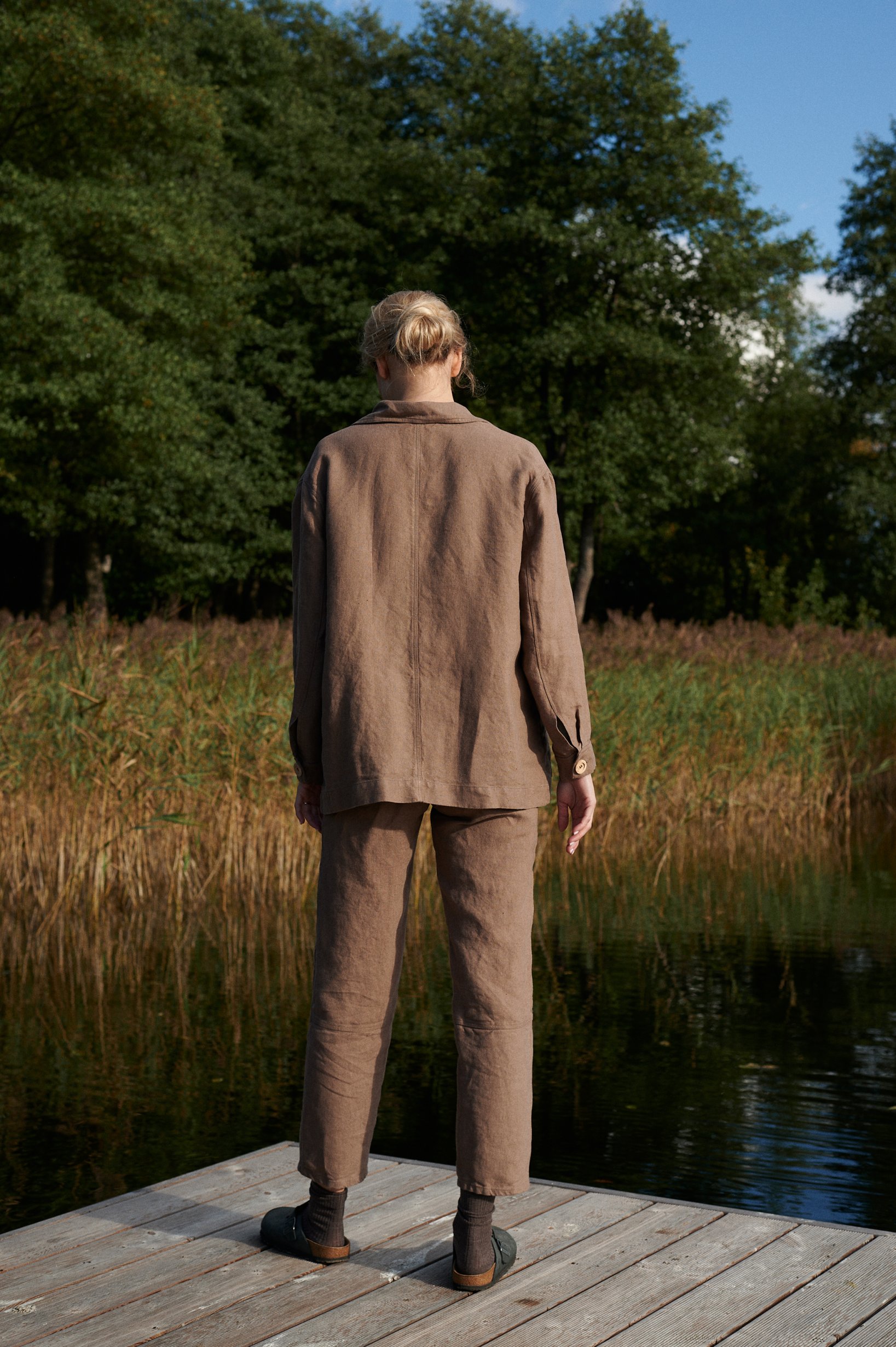 Back of a model wearing a brown linen utility jacket and pants