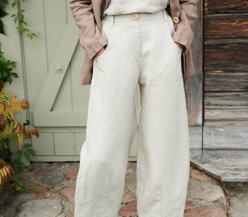 A woman in high waist barrel leg natural linen pants