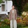 A woman standing in natural grey heavy linen barrel pants