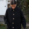 Front of a black linen utility jacket with patch pockets and wooden buttons