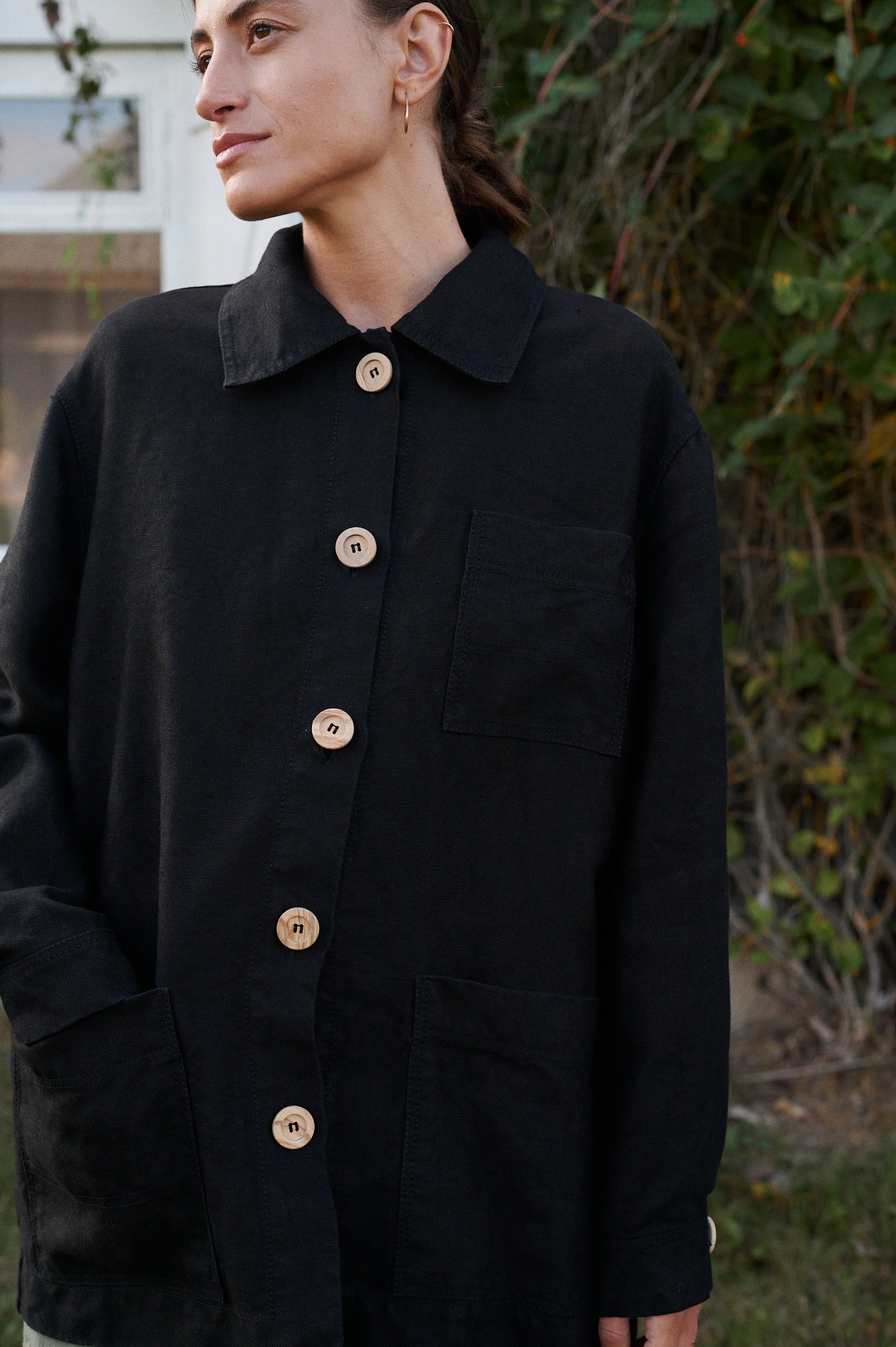 Front details of a linen utility jacket with three patch pockets and wooden buttons
