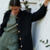 Black linen utility jacket paired with a green linen top tucked into trousers