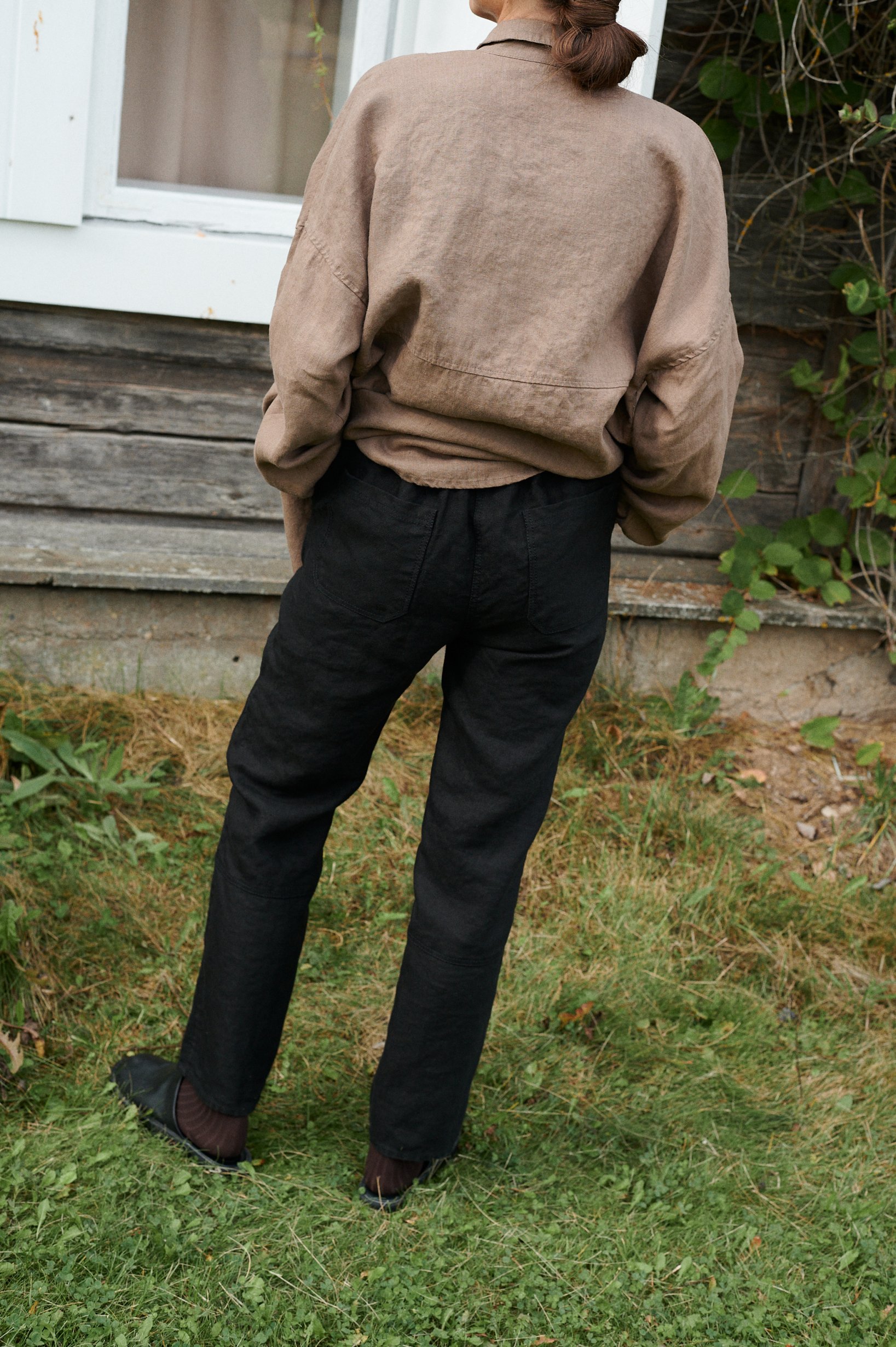 Back view of high-waisted black linen trousers with an elasticated waistband and two back pockets