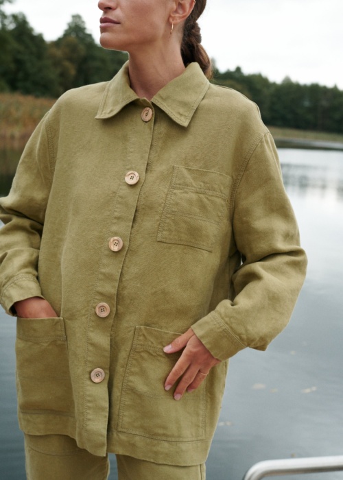 Woman in olive green linen outfit near lake