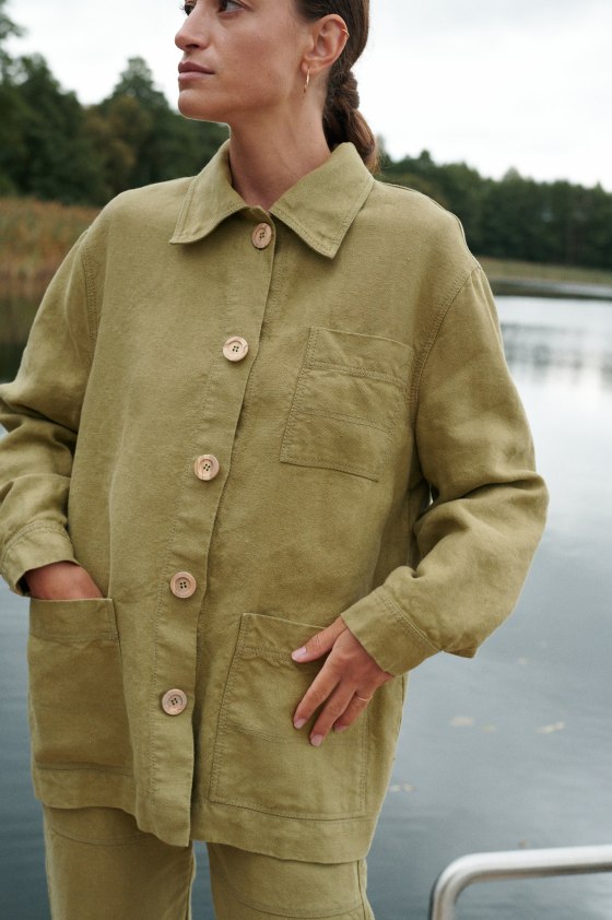 Women in olive green linen outfit near lake