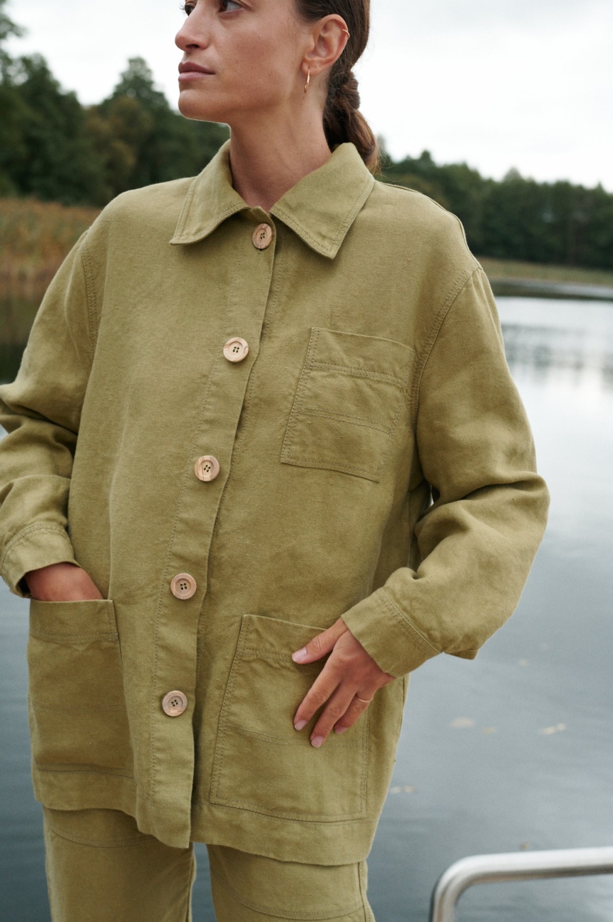 Woman in olive green linen outfit near lake