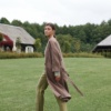 A model wearing a long brown linen jacket that's flowing as she's walking