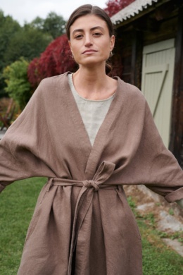 A model in a heavy cacao linen jacket with loose sleeves and a fastened matching belt