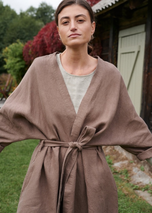 A model in a heavy cacao linen jacket with loose sleeves and a fastened matching belt