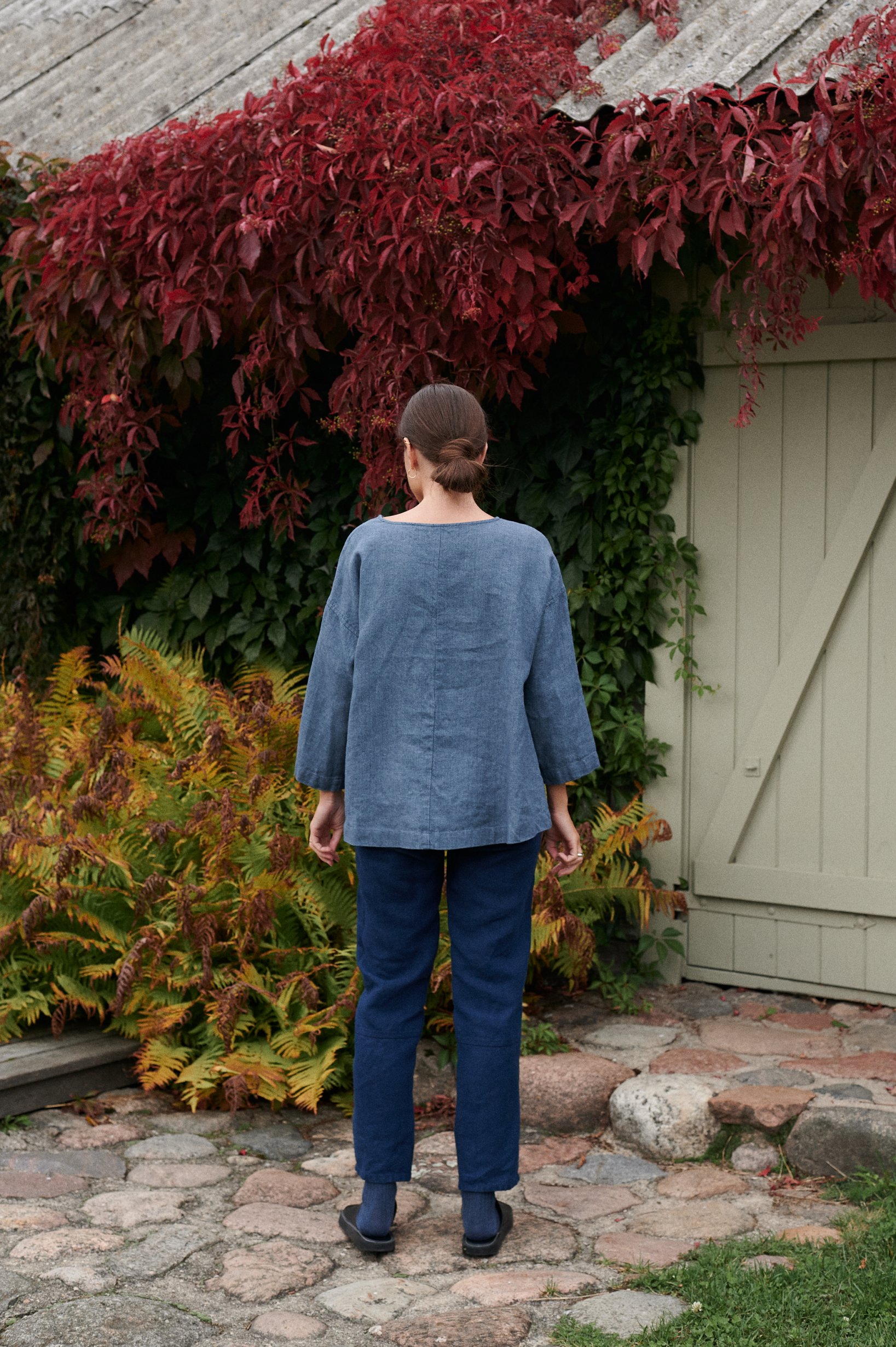Back of a loose fitting blue linen wool blend tunic and navy blue trousers