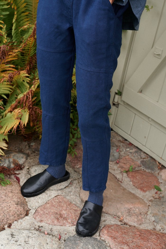 Tapered navy blue utility linen trousers with exposed seam details on the legs