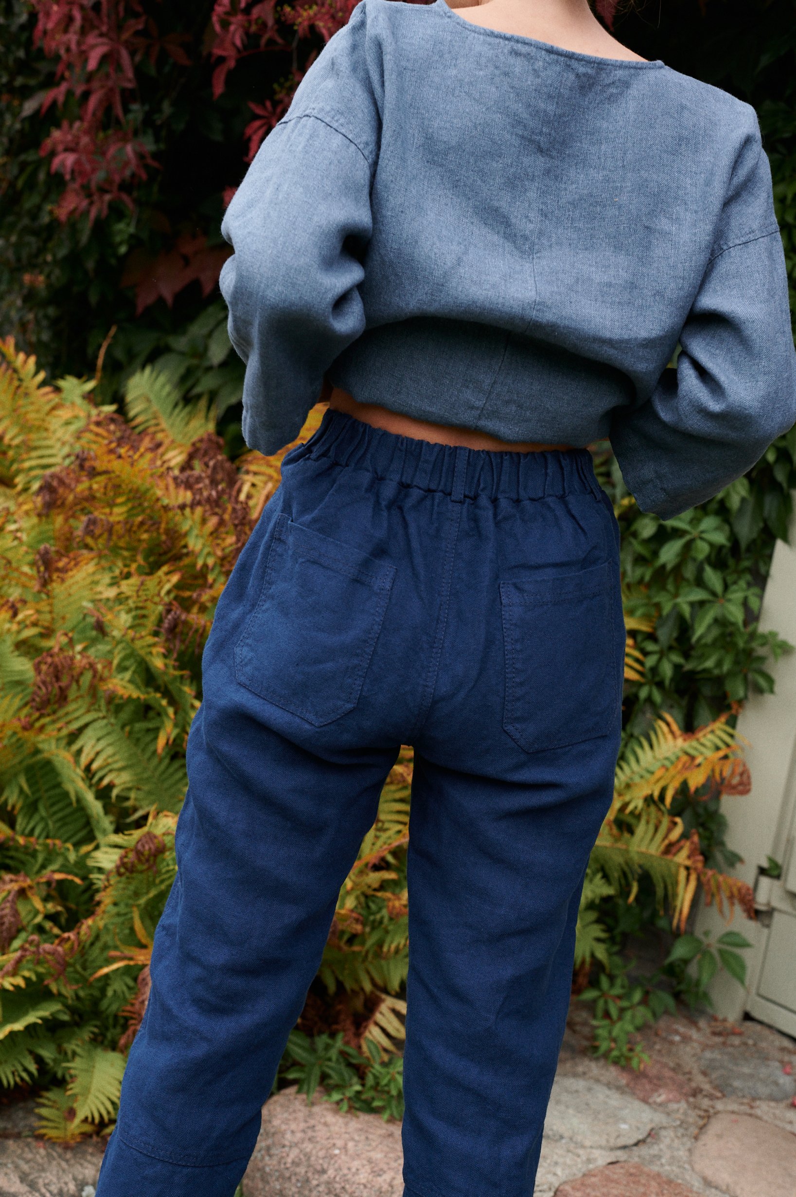 Backside of navy blur utility linen trousers with elasticated waist and two back pockets
