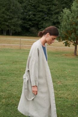 Side view of a model in a heavy natural grey linen jacket with a belt and pockets