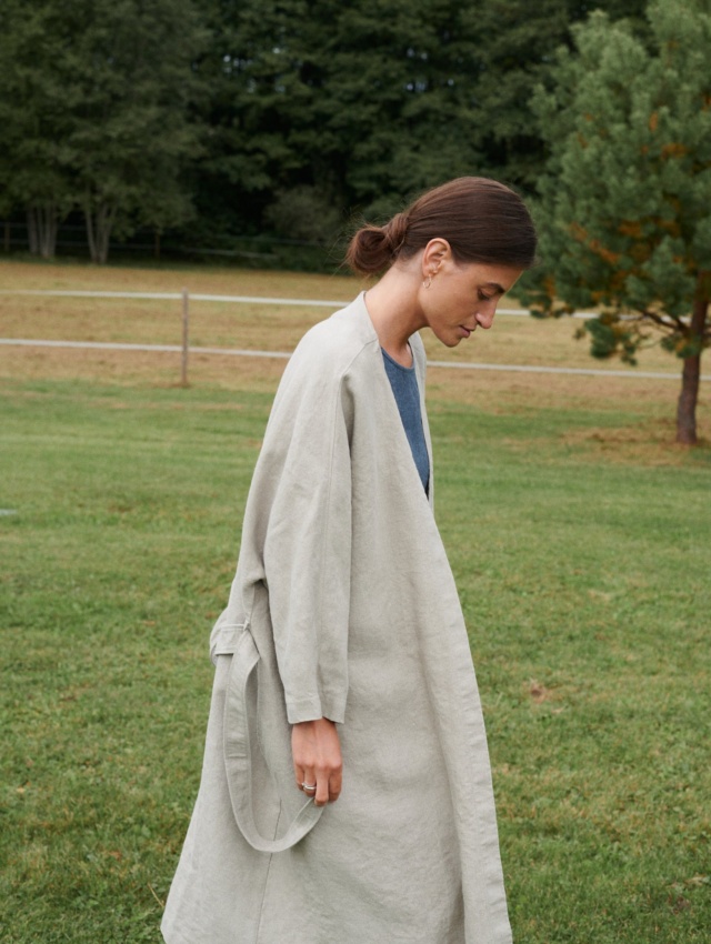 Side view of a model in a heavy natural grey linen jacket with a belt and pockets