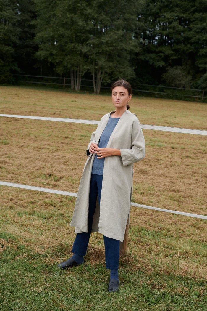 A woman in a long natural grey linen jacket untied