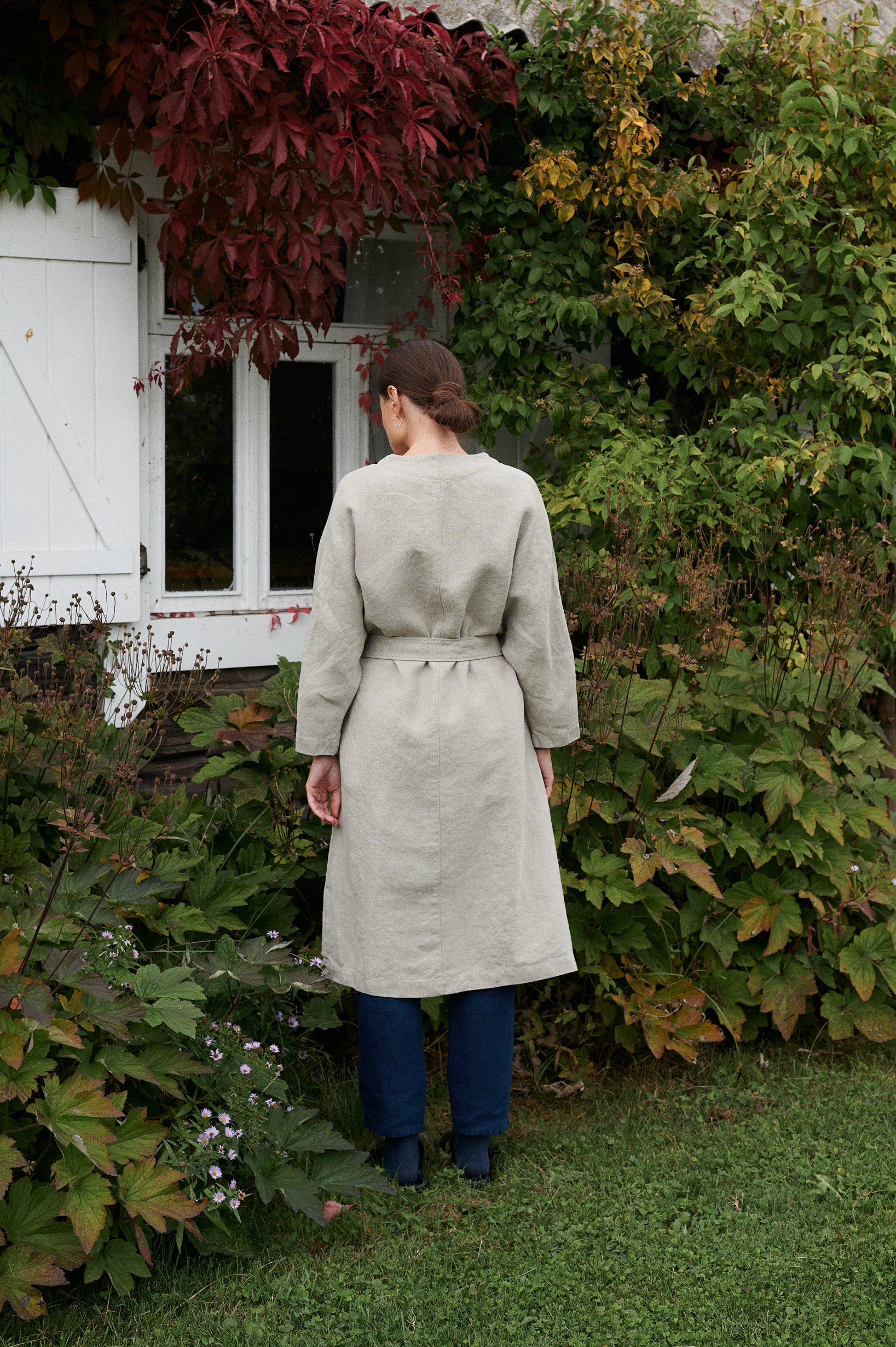 Back of a long relaxed fitting-natural grey linen jacket fastened with a belt