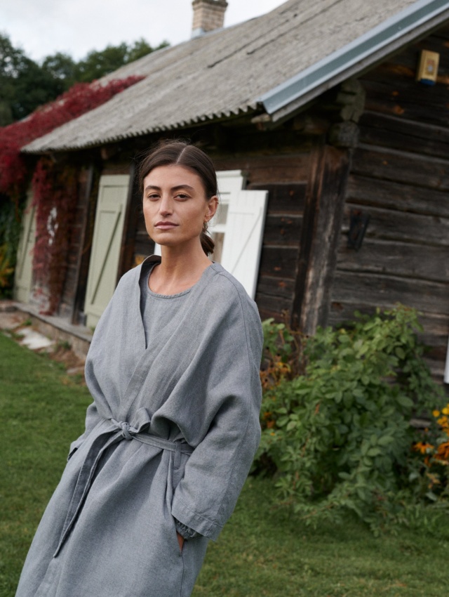 Woman wearing a grey linen wool blend oversized jacket with a matching belt tied around the waist