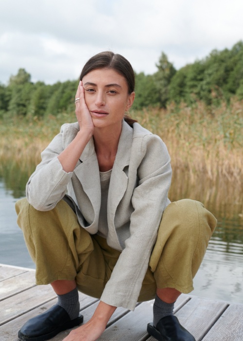 A woman squatting in olive green heavy linen trousers