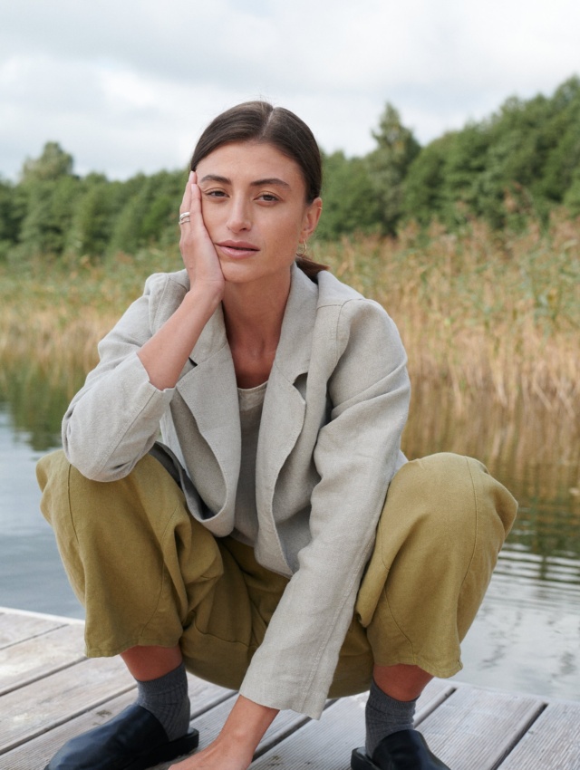 A woman squatting in olive green heavy linen trousers