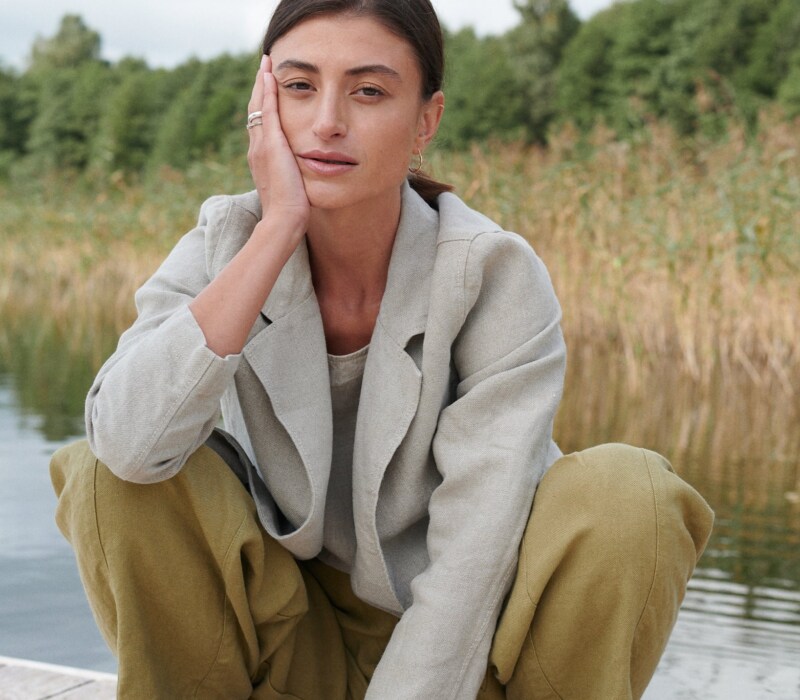 A woman squatting in olive green heavy linen trousers