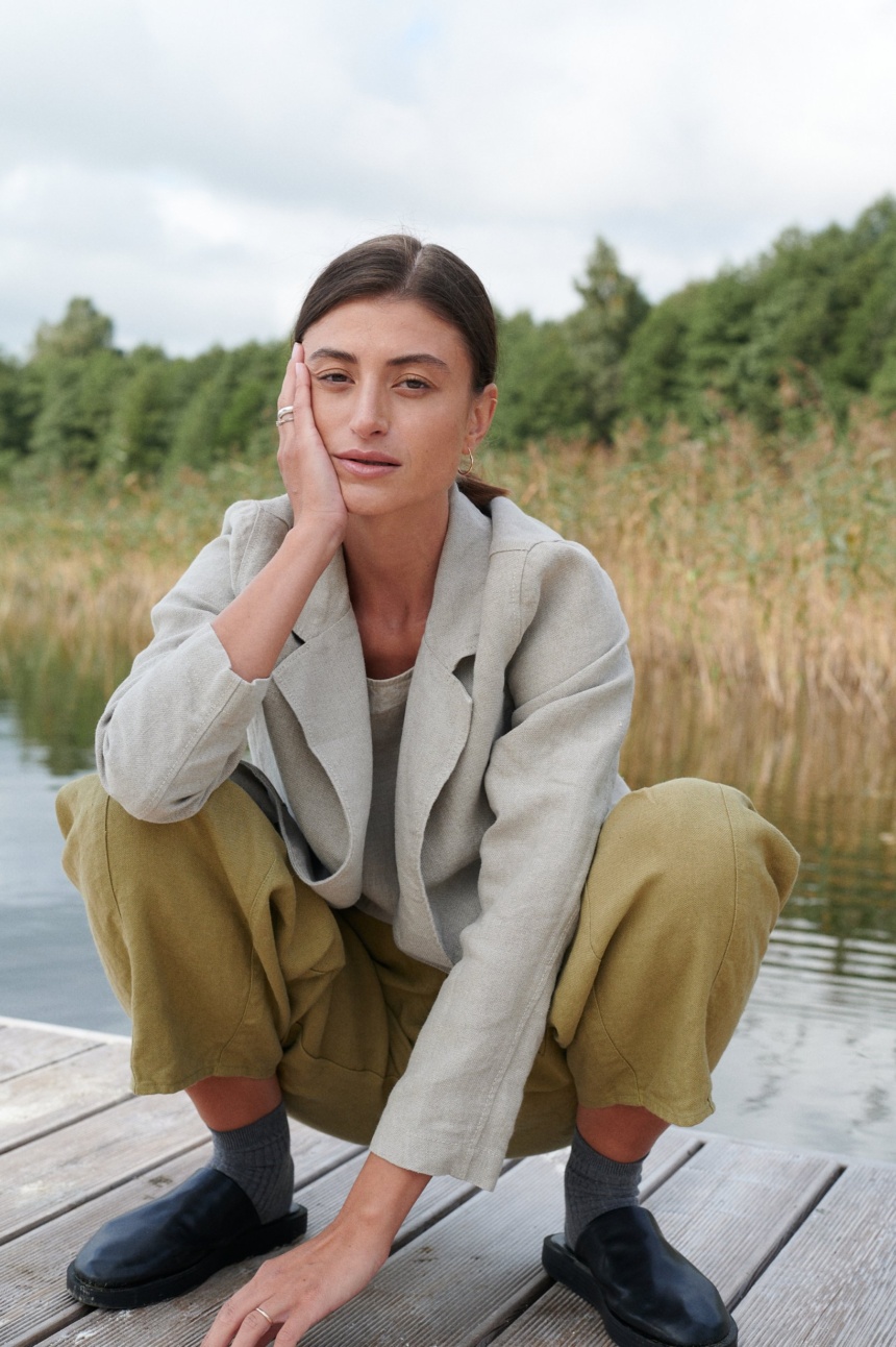 A woman squatting in olive green heavy linen trousers