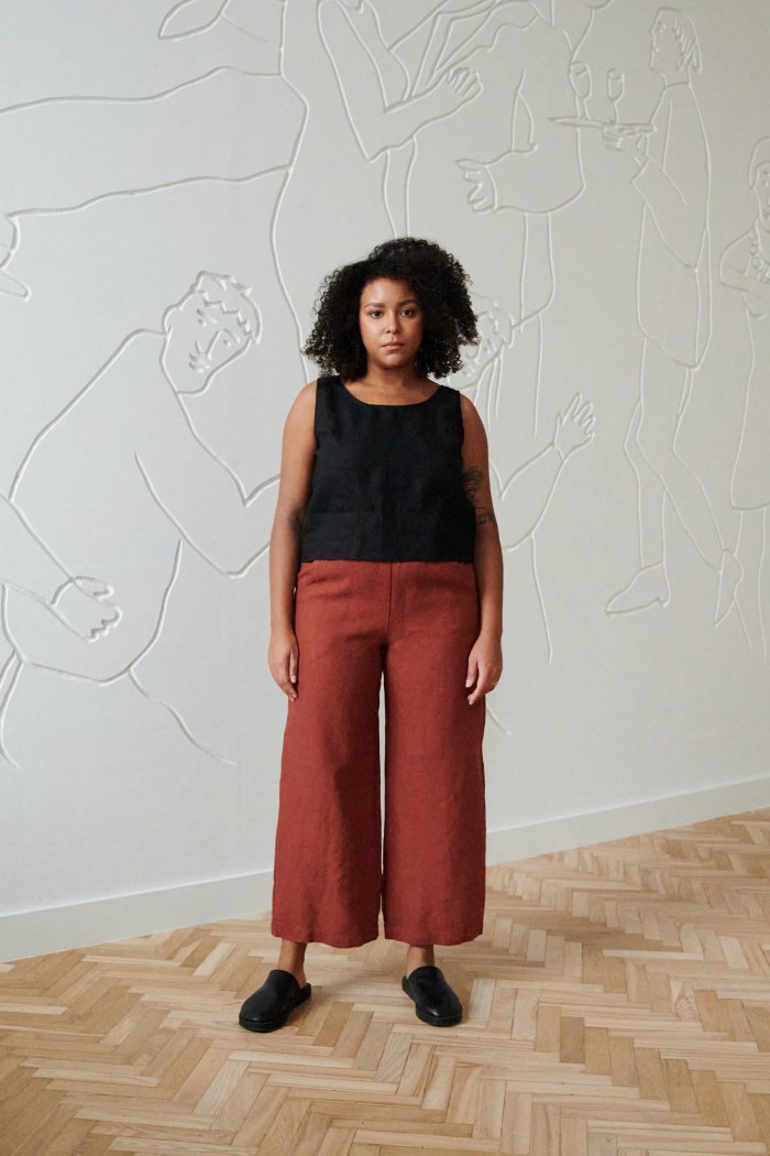 front of model in terracotta wide leg linen trousers paired with a black linen summer top with wide straps