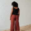 Back of a model in slightly cropped heavy linen trousers and a sleeveless linen top