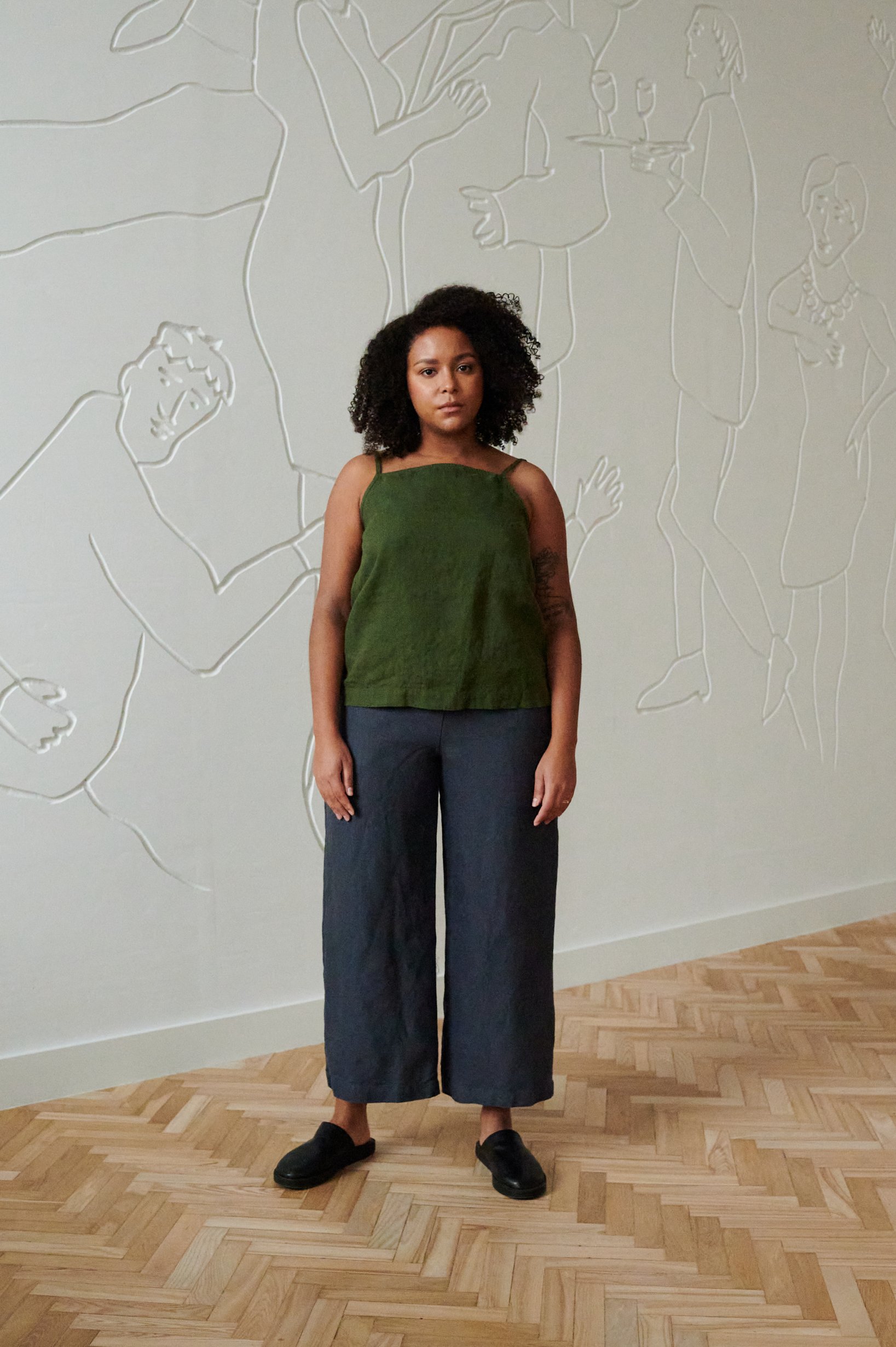 Front of a model in a linen summer top with thin straps and wide leg linen trousers outfit