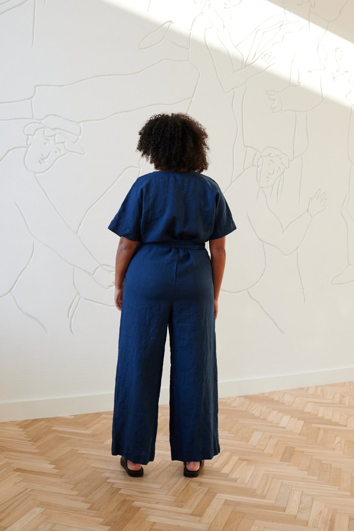 Back of a model wearing a blue linen jumpsuit with an attached belt