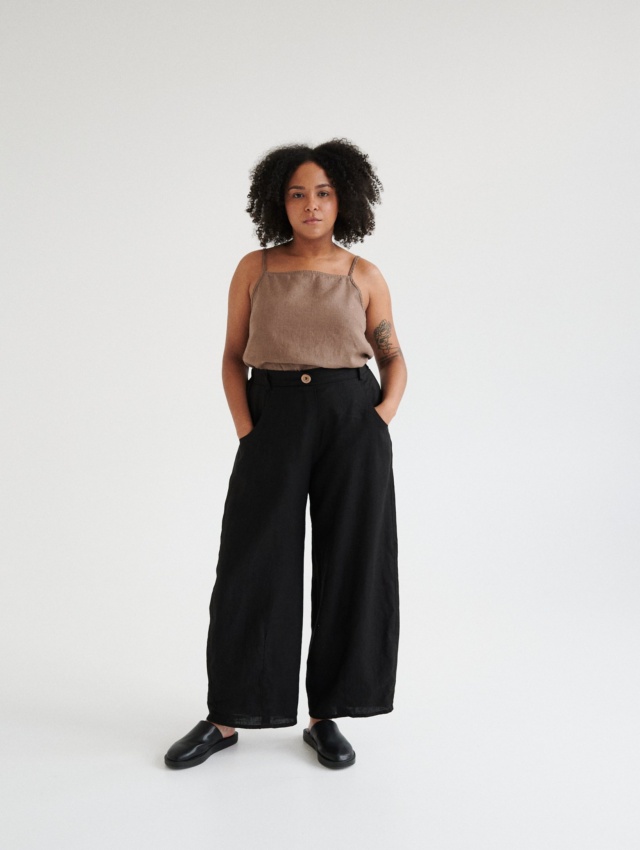 A woman wearing black linen barrel trousers.