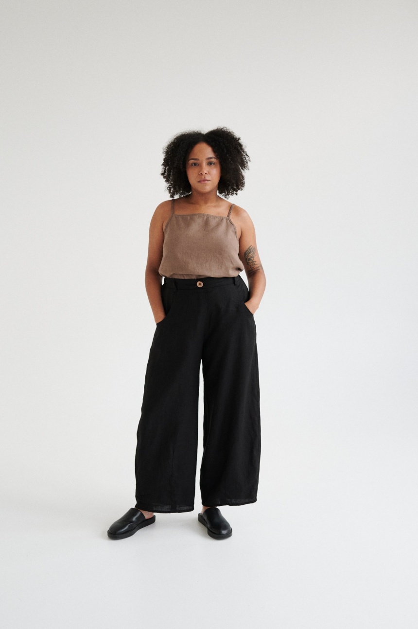 A woman wearing black linen barrel trousers.