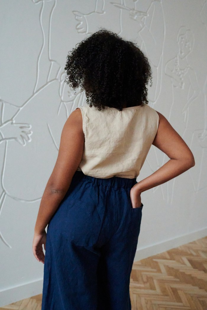 Back of a model in a beige linen to and high waisted linen trousers with back pockets