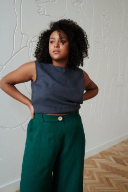 Model in a cropped sleeveless linen top and high waisted linen trousers with a wooden button