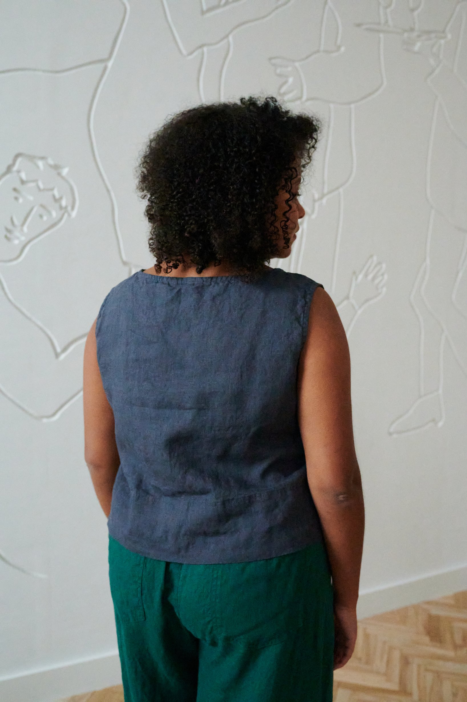 Back of a woman wearing a a loose-fitting sleeveless linen top