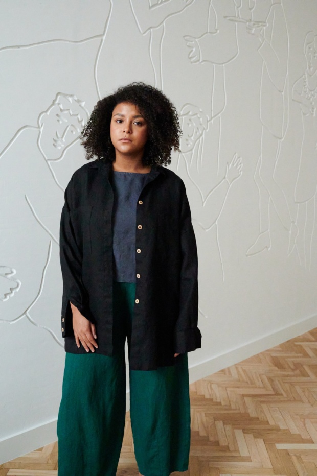 Model in a black loose-fitting linen button down shirt and relaxed linen trousers