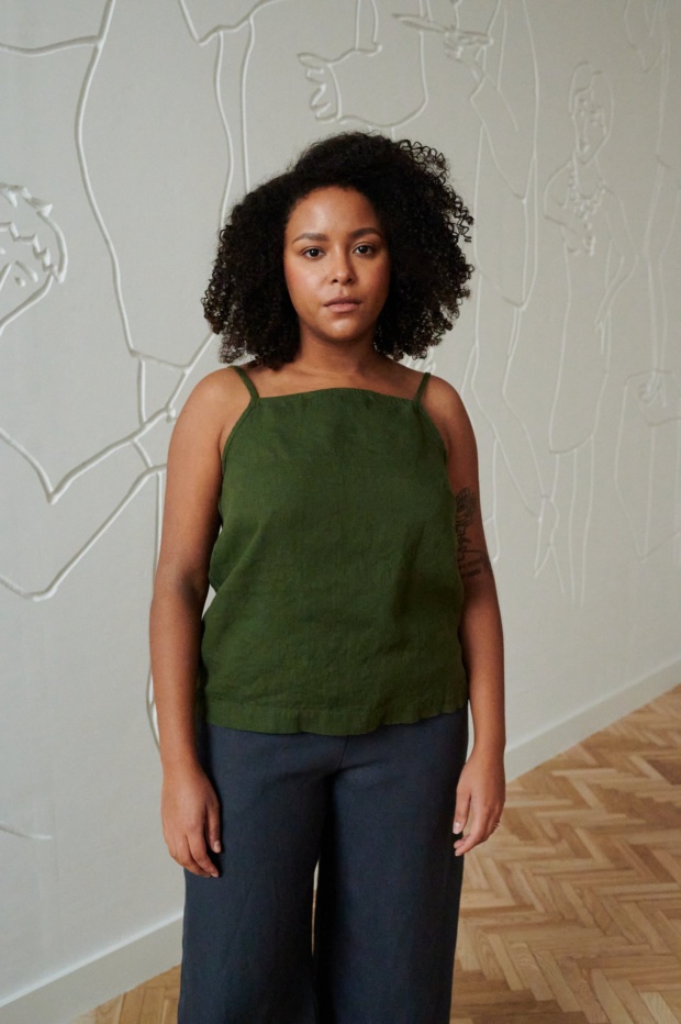 A model wearing a green straight-cut linen top with thin straps