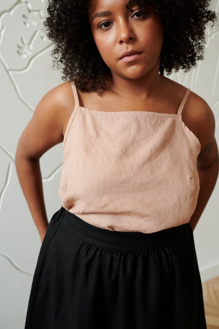 A linen summer top with a nigh neckline and straps tucked into the waist of a linen skirt