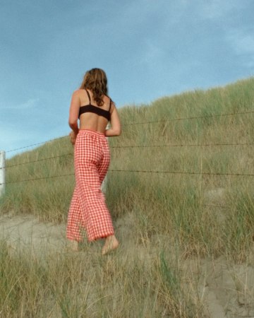 Back of a woman in relaxed-fit red gingham linen trousers