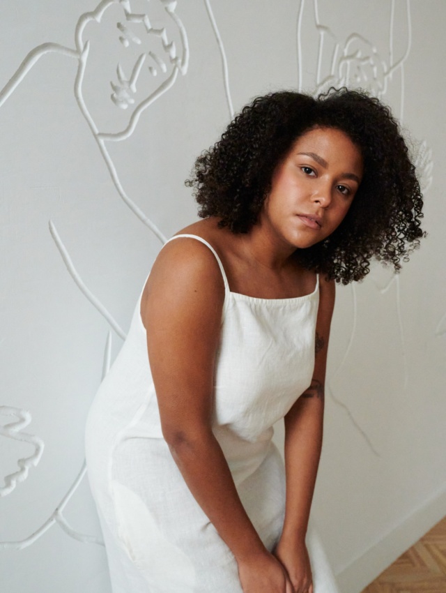 Model in a white linen dress with thin straps and a straight across neckline