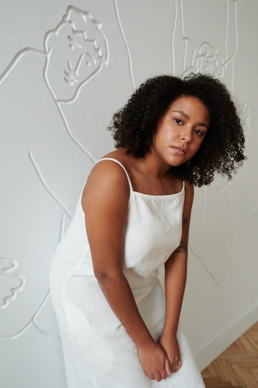 Model in a white linen dress with thin straps and a straight across neckline