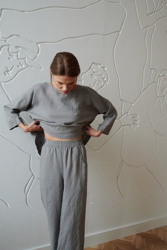 Woman wearing grey high waisted linen trousers and a matching oversized linen tunic