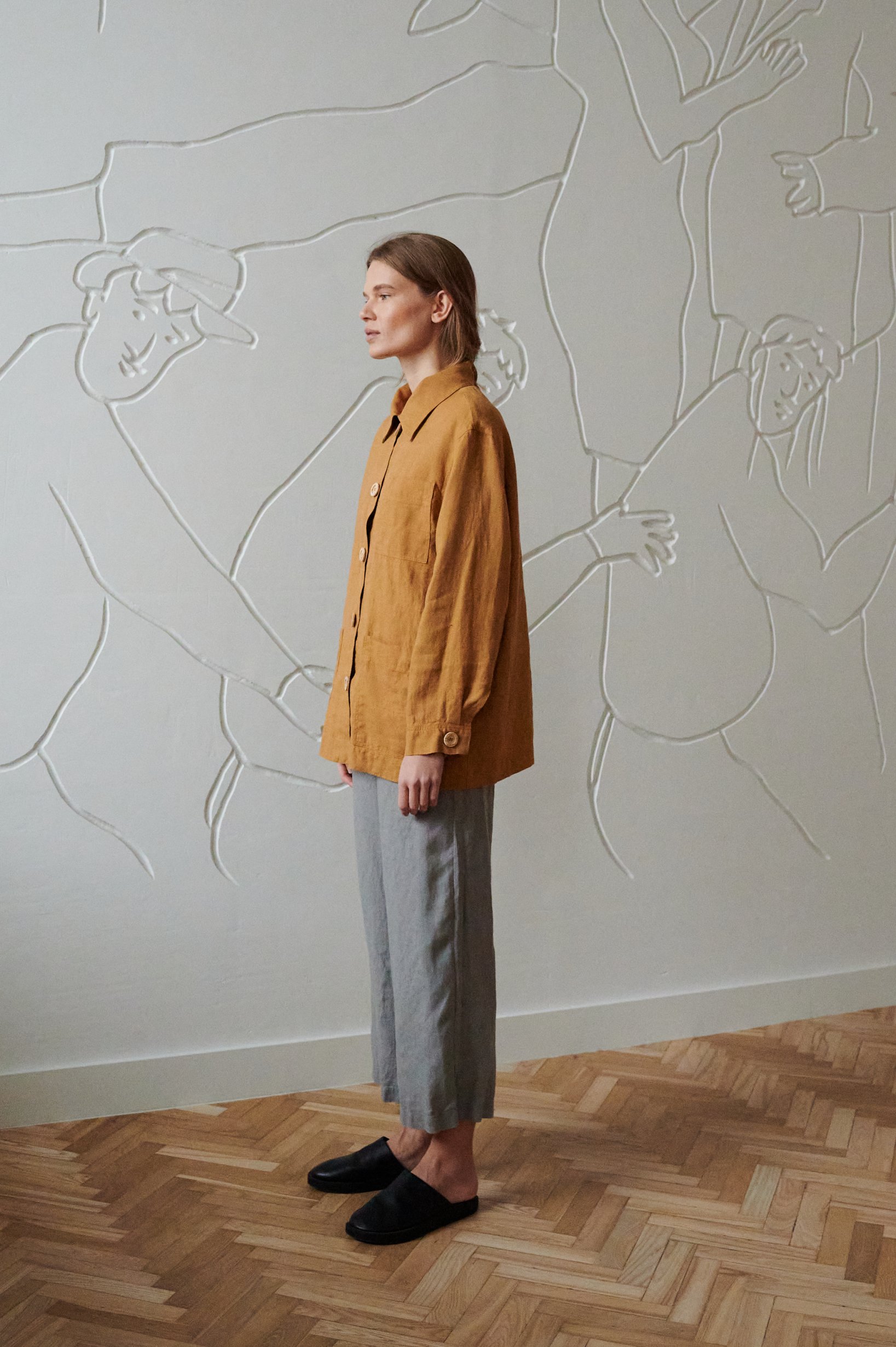 Side view of a model wearing wide-leg linen trousers and a relaxed fit utility linen jacket